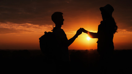 Naklejka na ściany i meble silhouette of lover couple having romantic moment holding hand in hand with background og sunset