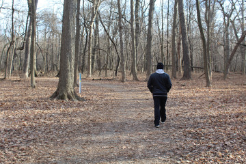 Man walking on a trail on a cold day at Campground Road Woods in Des Plaines, Illinois