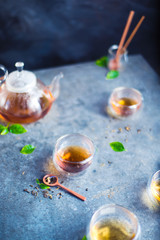 Relaxing teatime, glass tea set with leaves on a stone kitchen table