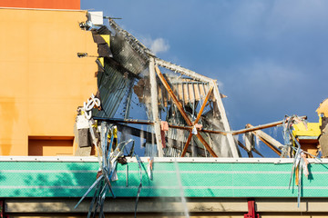 Commercial building collapsing during demolition job with a cloud of dust and large chunks of...