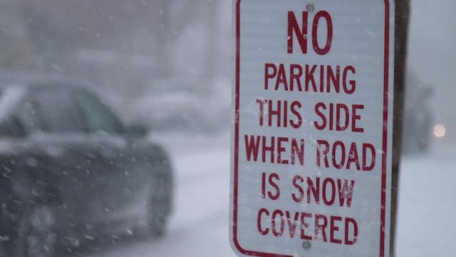 no parking this side when road is snow covered, street sign during a snow storm