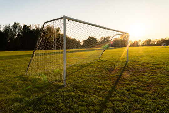 An empty soccer goal at sunset