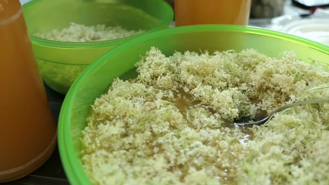 Prepare elder berry flower heads to making jam of it. Mixing apple juice into bowl.