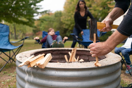 Father chopping wood with an axe at a campsite