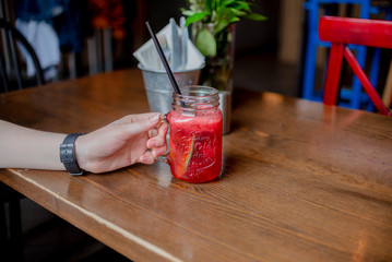 Woman hand holding smoothie shake on the table in a cafel. Drinking healthy smoothie concept.