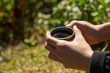 drinking Dripping Coffee or Filter coffee in the mountain and sunrise at camp with nature, Closed up at hand and a cup of dripping coffee in the afternoon or moring with green nature Background