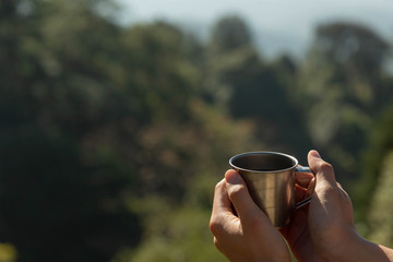 drinking Dripping Coffee or Filter coffee in the mountain and sunrise at camp with nature, Closed up at hand and a cup of dripping coffee in the afternoon or moring with green nature Background