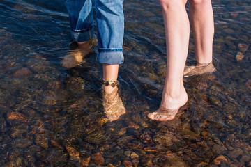 Two women with bare feet standing in the river