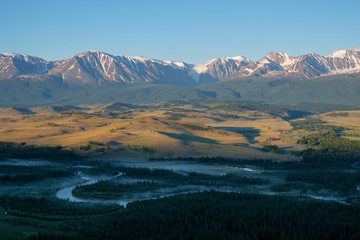 Summer morning in the Chuy valley, snow-capped peaks of mountains, fog over the river. Dawn in the mountains of Altai.