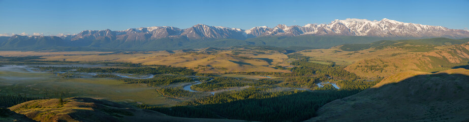 Summer morning in the Chuy valley, snow-capped peaks of mountains, fog over the river. Dawn in the mountains of Altai, panorama.