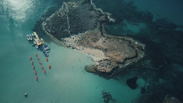 Aerial top down view of a small island in Cyprus. Boats parked next to a dock, Nissi Beach. Ayia Napa, Cyprus.