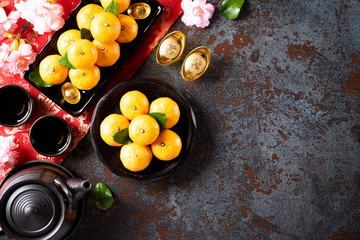 Chinese new year festival decorations pow or red packet, orange and gold ingots or golden lump on a black stone texture background. Chinese characters FU means fortune good luck, wealth, money flow.