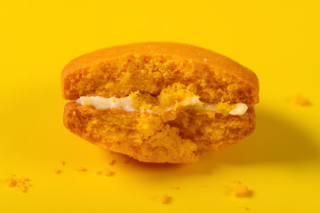 half eaten brown macaroon on yellow background