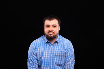 A young, bearded, charismatic man in a blue shirt on a black background.