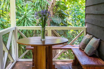 Wooden bench with pillows and table with a vase of flowers on a wooden veranda, Tanzania, Africa, close up