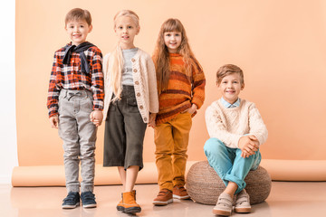 Cute little children in autumn clothes near color wall