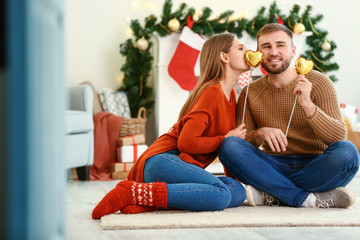 Happy young couple with hearts at home on Christmas eve