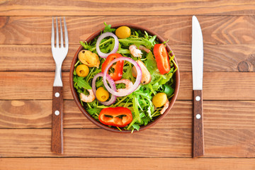 Plate with tasty salad on wooden table