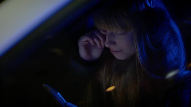 Crying woman seated in car wiping a tear