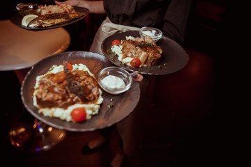 the waiter is holding a beef steak with mashed potatoes