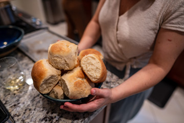 Woman holding bowl of freshly cooked rolls in preparation for home dinner
