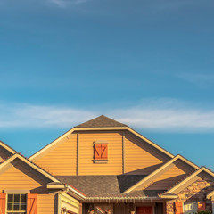 Square House exterior with view of the gable roof with gable windows against blue sky
