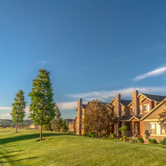 Fototapeta premium Square frame Beautiful homes on a neighborhood with lush lawn road trees and mountain views