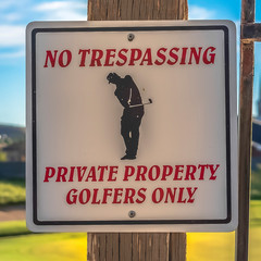 Square frame No Trespassing sign with blurry golf course homes mounntain and sky background