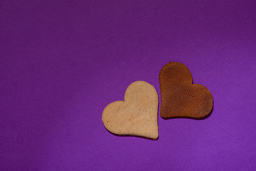 Two heart cookies are on a purple background for Valentine's Day