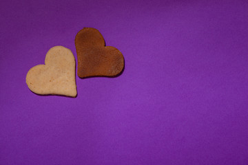 Two heart cookies are on a purple background for Valentine's Day