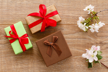 Gift boxes with cherry flowers on the wooden background.