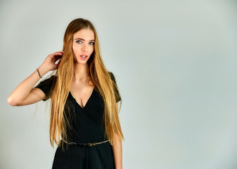 The concept of fashion and style. Portrait of a pretty blonde girl with long hair and great makeup on a white background. The model stands in different poses in front of the camera.