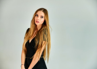 Fototapeta premium The concept of fashion and style. Portrait of a pretty blonde girl with long hair and great makeup on a white background. The model stands in different poses in front of the camera.