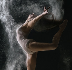 Concept. Flexible girl dancing in cloud of dust