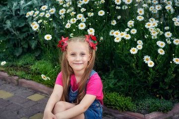 Portrait of a little girl on the background of a garden Daisy
