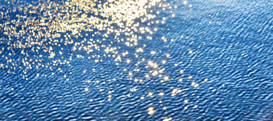 Golden blurred sun stars are reflected in the water. Nature background.