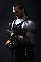 Portrait of a medieval knight with a two-handed sword in the dark. Silhouette Warrior in the studio...