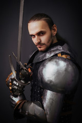 Portrait of a medieval knight with a two-handed sword. Warrior in the studio on a dark background.