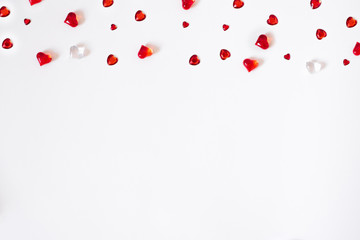 Confetti of red hearts. A scatter of a cornered border on a white Valentine background