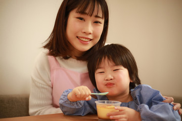 おやつを食べる男の子と保育士イメージ