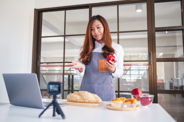 A beautiful asian woman food blogger or vlogger recording a video on camera