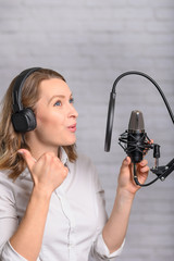 A girl works with a microphone, recordings Audio recording on the radio, or dubbing an audiobook,...