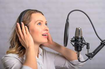 Emotional reading a girl news on the radio, in the studio with a studio microphone. Podcasts, television, vlogs. Sound and reading audio books.