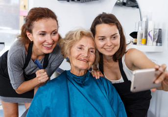 Obraz premium Hairstylists and female customer taking selfie