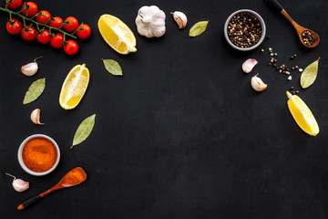 Kitchen frame with spices and food - pepper, garlic, cherry tomatoes - on black background top-down frame copy space