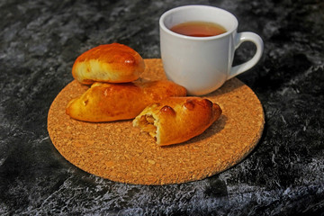 Pies with cabbage and eggs. Baked stuffed patties and cup of tea. Rustic photo. Copy space