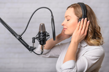 Emotional reading a girl news on the radio, in the studio with a studio microphone. Podcasts,...