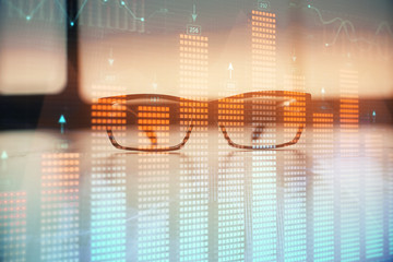 Financial graph hologram with glasses on the table background. Concept of business. Double exposure.