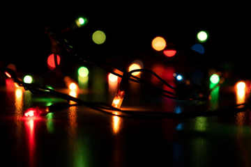 New Year's Christmas multi-colored lights on a dark background with a bokeh effect. New Year's Christmas mood