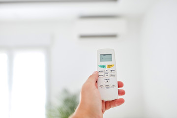 Modern air conditioner unit with a hand holding a remote.